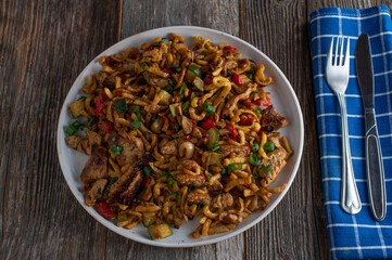 Pasta dish with meat and vegetables on a plate. Cooked with german spaetzle noodles