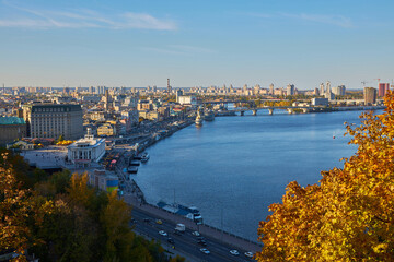 Obraz premium View from the Glass Bridge to the city center, road, cars. Public transport. View of the Dnieper river with rocks, green hills and boats. Kyiv. Urban city life.