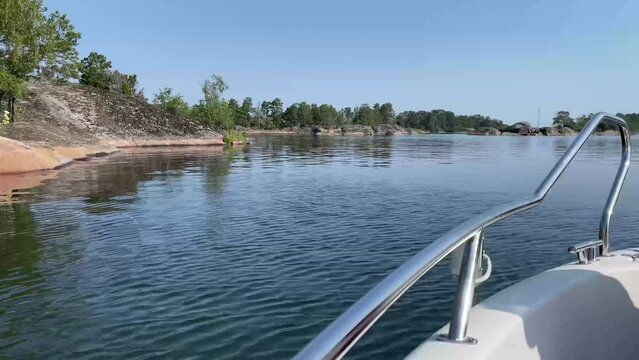View from a boat that is driving through the calm water between the islands in the Swedish archipelago and coastal landscape on a summer day. Footage made in Sweden. User generated content.
