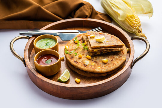Sweet corn stuffed paratha or parotha served in a plate, Indian flatbread recipe made filling makai