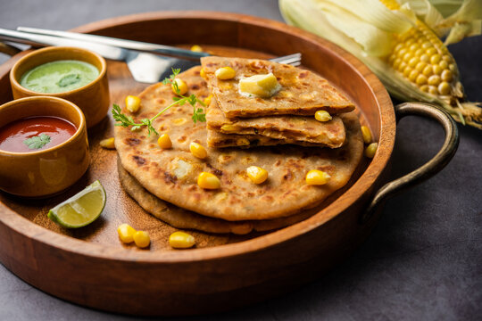 Sweet corn stuffed paratha or parotha served in a plate, Indian flatbread recipe made filling makai