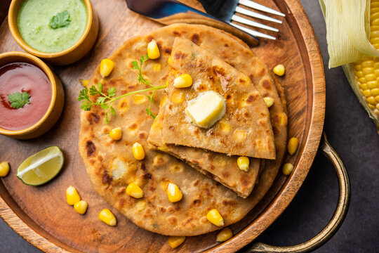 Sweet corn stuffed paratha or parotha served in a plate, Indian flatbread recipe made filling makai