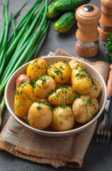 Boiled potatoes with dill and butter close-up on a dark background. Side view, vertical