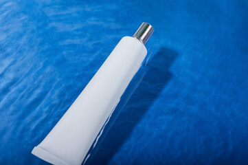 White tube for cream on the water surface. The concept of natural cosmetics.