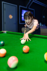 A beautiful woman playing pool in a recreation room
