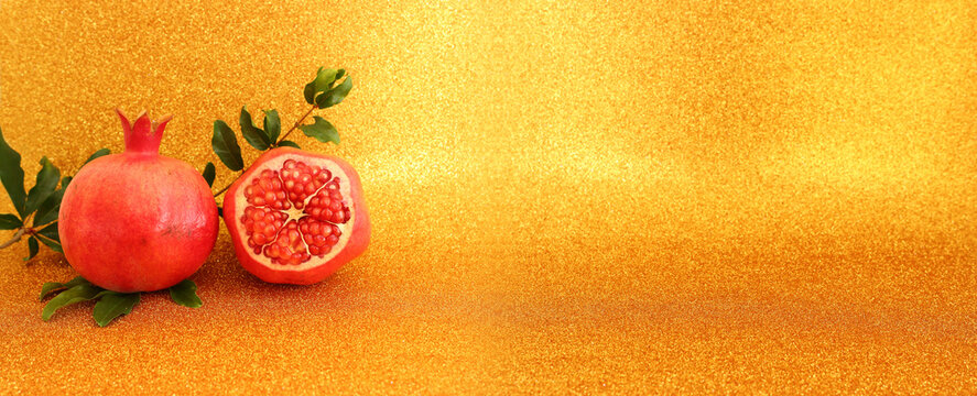 Rosh hashanah (jewish New Year holiday) concept. Pomegranate raditional symbol over gold glitter background