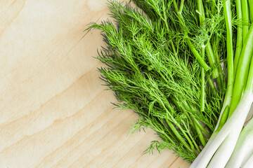 Greens, dill, onion and a sandwich with a knife lie on the cutting board