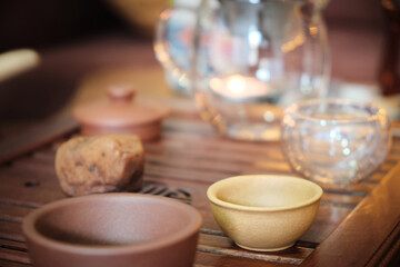Traditional chinese tea ceremony utensils on a tea tray. Chinese teapots made of brown yixing clay and glass and tea bowls. Tea brewing equipment low key dark mood