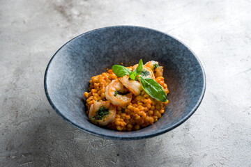 Risotto with shrimp and basil on grey plate on grey table