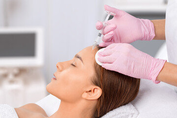 Cosmetologist makes rejuvenating anti wrinkle injections on the face of a beautiful woman. Female aesthetic cosmetology in a beauty salon.