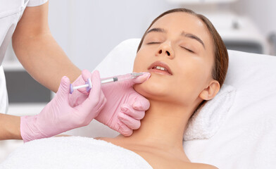 Cosmetologist does injections for lips augmentation and anti wrinkle in the nasolabial folds of a...