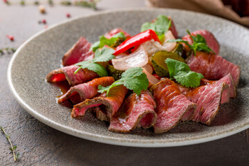 Sliced roast beef on plate on brown table macro close up