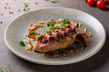 Bruschetta with roast beef on brown plate macro close up