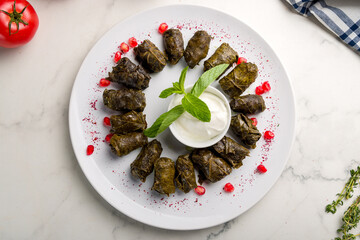 Dolma with sour cream on white plate georgian kitchen on marble table top view