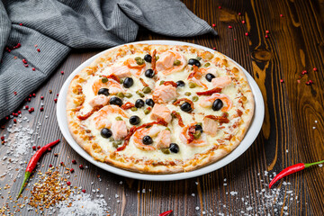 Pizza with salmon and shrimps on wooden table