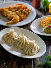 Khinkali with lamb on white plate, georgian cuisine on old wooden table