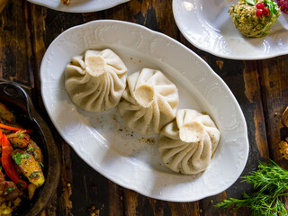 Khinkali with lamb on white plate, georgian cuisine on old wooden table