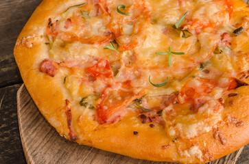 Pizza with cheese and tomatoes on a wooden background close-up