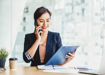 Young Attractive Asian business female manager talking on the phone with business client.