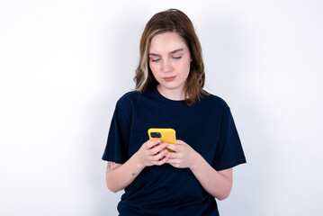 Excited young caucasian woman wearing black T-shirt over white background winking and eye hold smart phone use read social network news