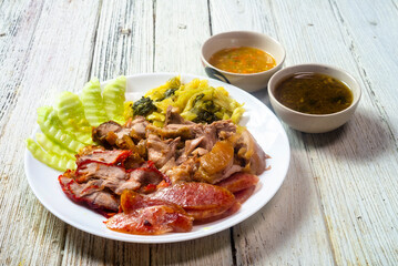 Pork Leg Stew, Red Pork, Crispy Pork and Chinese Sausage served with pickled lettuce and cucumber in a white plate.