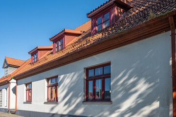 View of impressive renovated white building with terracotta tiled roof with blue sky in the background on a sunny summer day.
