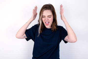 young caucasian woman wearing black T-shirt over white background goes crazy as head goes around...