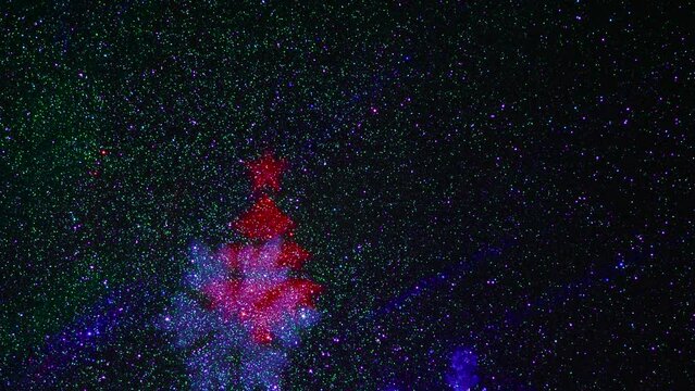 A carousel of light beams of different colors is set against a constantly flashing background that changes colors. Flying colored silhouettes of Christmas trees and snowflakes.
