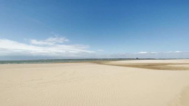 (Slow-Mo) Sanlucar de Barrameda beach in Spain. This beach is formed by water from the mouth of the Gualdalquivir River and the Atlantic Ocean, with the 'Coto Do&ntilde;ana' National Park in front.