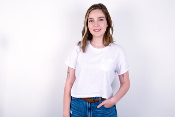 Portrait of successful young caucasian woman wearing white T-shirt over white background, smiling broadly with self-assured expression. Confidence and business concept.