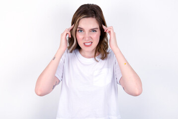 young caucasian woman wearing white T-shirt over white background concentrating hard on an idea with a serious look, thinking with both index fingers pointing to forehead.