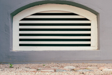 Close-up of arched ventilation window with vents of basement of renovated building with cobblestone...