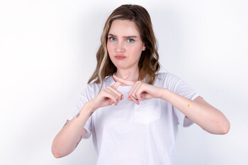 young caucasian woman wearing white T-shirt over white background has rejection angry expression crossing fingers doing negative sign.