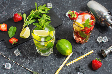 Fresh Mojito cocktail set with lime, mint, strawberry and ice in glass on stone background. Steel bar tools.