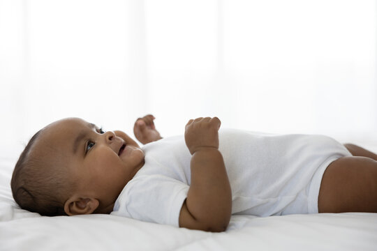 cute African baby lying on bed at home
