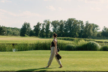 Beautiful girl walking barefoot on the green grass in the park on a sunny day