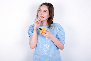 Image of a thinking dreaming young caucasian woman wearing blue T-shirt over white background using...