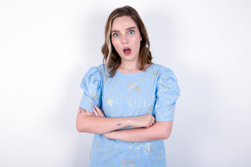 Shocked embarrassed young caucasian woman wearing blue T-shirt over white background keeps mouth...