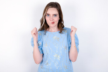 Irritated young caucasian woman wearing blue T-shirt over white background blows cheeks with anger...