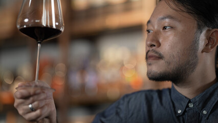 Night club concept of 4k Resolution. Asian man tasting wine in a restaurant. A group of specialized clubs that sell alcoholic beverages.