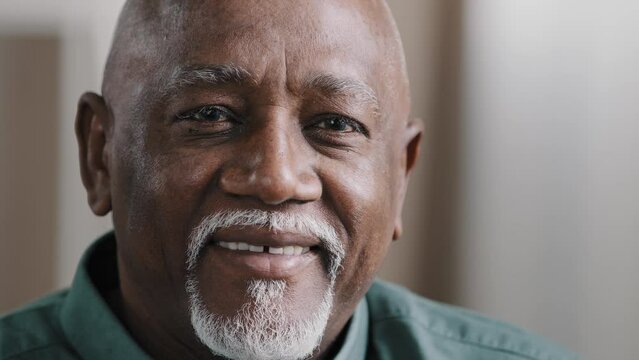 Portrait close clever serious pensive male wrinkled face with gray beard bald African old senior mature thoughtful businessman looking away thinking pondering turning head looks at camera smiling