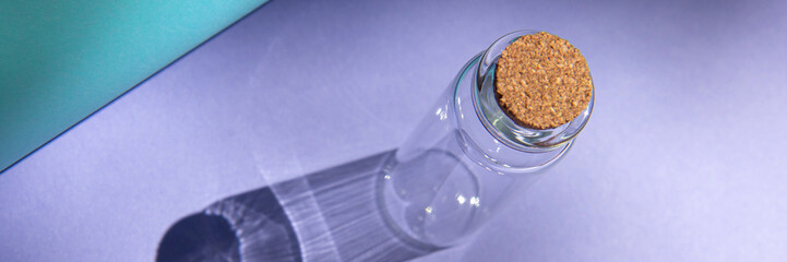 Modern apothecary concept. Empty glass miniature bottle with cork cap on a blue background. Still life compositions