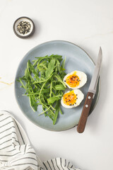 boiled eggs with arugula on a gray plate on gray background.