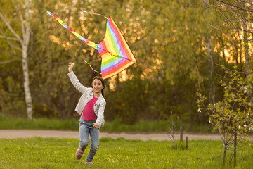 Little girl flying a kite running outdoor with a kite