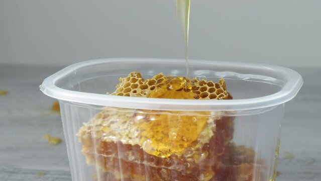 Dripping honey on the Pieces of sweet honeycomb in the plastic containers