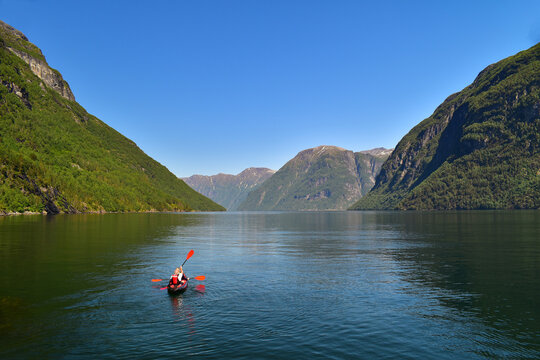 Couple kayaking across fjord in Geiranger region, Norway