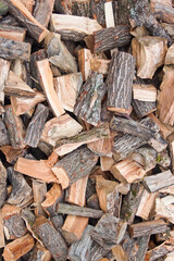 A pile of scattered firewood chopped from logs of deciduous trees. Autumn preparation for the heating season. Acacia wood logs. Natural fuel for fireplaces and barbecues.