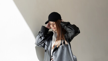 Beautiful young girl in a fashionable black cap with a stylish leather jacket and hoodie walks in...