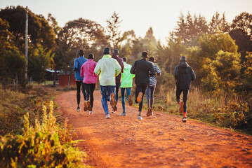 Morning running training in Kenya. A group of endurance runners run on red soil at sunrise. Morning...