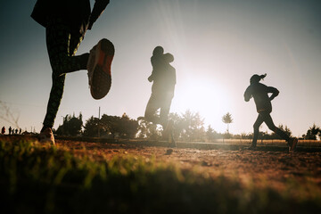 Morning running training in Kenya. A group of endurance runners run on red soil at sunrise. Morning...
